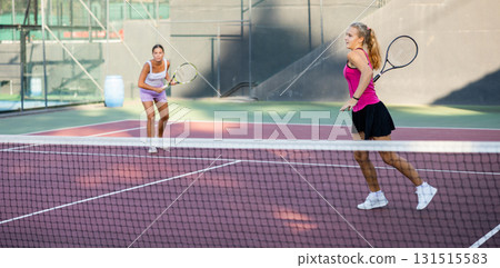 Girl playing tennis ball friendly match on outdoors court Girl playing tennis ball friendly match on outdoors court 131515583