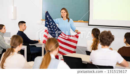 Adult female teacher showing US flag to students 131515617