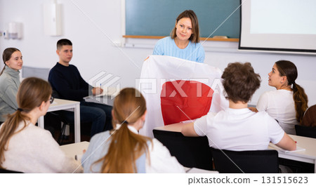 Adult female teacher showing students the flag of Japan 131515623