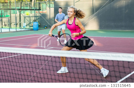 Girl playing tennis ball friendly match on outdoors court 131515645