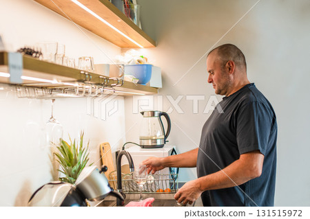 Middle-aged man washing dishes in the kitchen. Middle-aged man washing dishes in the kitchen. 131515972