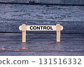 Control symbol. Wooden stick fastened by Clothespins, A lightly orange toned grunge wooden background. Business and Control concept with copy space 131516332