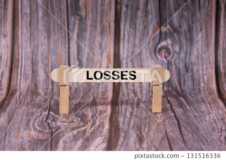 Losses symbol. A wooden stick clasped by clothespins set over a beautiful Brown Grunge Wooden Texture Background. Business and Losses concept with copy space 131516336