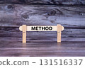Method symbol. A wooden stick secured by Clothespins set over beautiful Realistic Wooden Texture Background. Business and Method concept with copy space 131516337