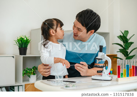 father and toddler girl scientist placing microscope slides with specimen. learning science father and toddler girl scientist placing microscope slides with specimen. learning science 131517838