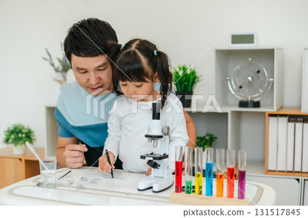 toddler girl scientist using tongs putting small herbal sample in slide with father, preparing specimen for science microscope 131517845