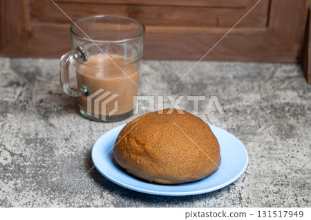 Deliciously baked coffee bun alongside a warm drink, perfect for a cozy morning or afternoon treat. Deliciously baked coffee bun alongside a warm drink, perfect for a cozy morning or afternoon treat. 131517949