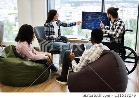 Group of diverse individuals discussing car design concepts with blueprint on monitor. Collaboration 131518279