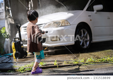 5-year-old boy washing a car with a pressure washer 131518699