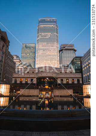 Twilight view of Canary Wharf in London, featuring One Canada Square and modern skyscrapers, with a reflective water feature and plaza in the foreground. Twilight view of Canary Wharf in London, featuring One Canada Square and modern skyscrapers, with a reflective water feature and plaza in the foreground. 131518734