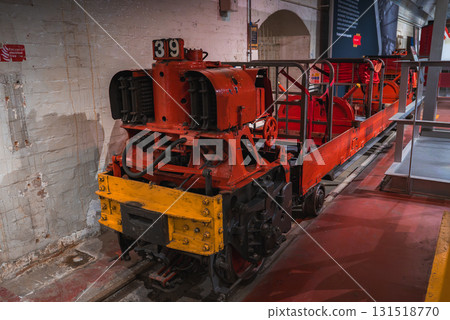 A red and yellow industrial locomotive with number 39 on tracks indoors, set against brick walls and arched doorways in a historical museum setting. 131518770