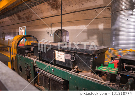 Indoor display of a green and black locomotive labeled 'Cell Explosion' in a brick walled underground space with arched doorways and visible piping. 131518774