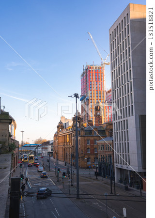 Manchester street scene featuring a red brick building with a clock tower, a modern high rise under construction, and a yellow double decker bus. Manchester street scene featuring a red brick building with a clock tower, a modern high rise under construction, and a yellow double decker bus. 131518821