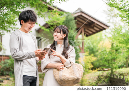 一對年輕的亞洲夫婦參觀旅遊景點，並在智慧型手機上搜尋資訊（應用程式、旅行、旅遊、美食） 131519090