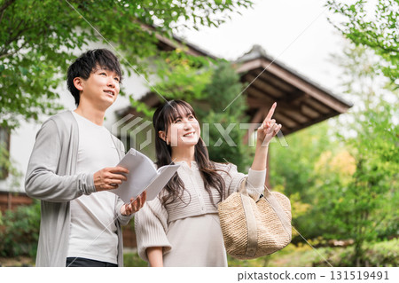 一對年輕夫婦在旅途中一邊看旅遊指南一邊尋找目的地 131519491