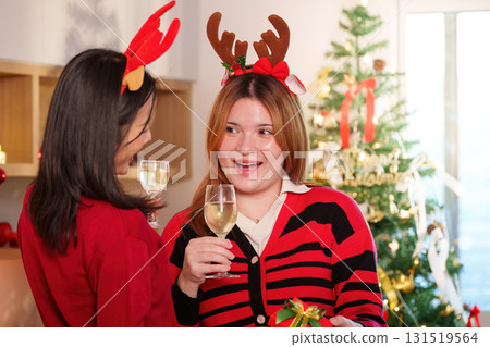 Holiday Celebration. Two friends enjoying festive drinks and exchanging gifts during Christmas party. Holiday Celebration. Two friends enjoying festive drinks and exchanging gifts during Christmas party. 131519564