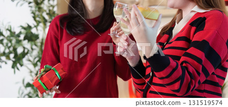 Festive Gathering. Two women sharing drinks and gifts at a Christmas celebration. Festive Gathering. Two women sharing drinks and gifts at a Christmas celebration. 131519574