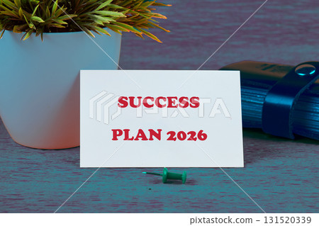 A clear success plan for the year 2026 is presented on a card beside a small green push pin and a potted plant, symbolizing growth and strategic planning in business A clear success plan for the year 2026 is presented on a card beside a small green push pin and a potted plant, symbolizing growth and strategic planning in business 131520339