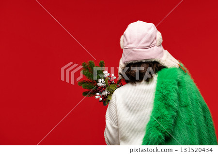 Woman in winter hat and green coat holding festive bouquet. 131520434