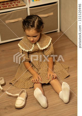 Young girl in polka dot dress preparing beige shoes 131520446