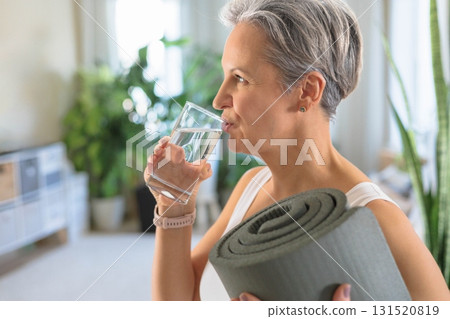 Happy smiling mature middle-aged woman with gray hair holding rolled yoga mat Happy smiling mature middle-aged woman with gray hair holding rolled yoga mat 131520819