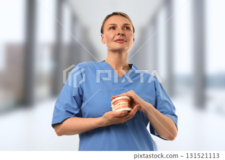 Expert in blue scrubs holds dental model in a modern clinic Expert in blue scrubs holds dental model in a modern clinic 131521113