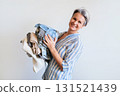Mature gray haired woman holding stack of clothes isolated on white background 131521439