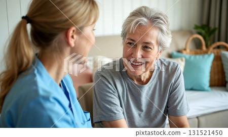 A cheerful female caregiver providing emotional support to a happy elderly woman at home. A cheerful female caregiver providing emotional support to a happy elderly woman at home. 131521450