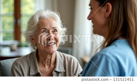 A cheerful female caregiver providing emotional support to a happy elderly woman at home. 131521451