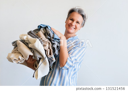 Mature gray haired woman holding stack of clothes isolated on white background 131521456