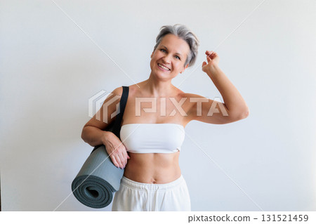 Smiling mature gray haired sport woman with yoga roll mat posing isolated on white background 131521459