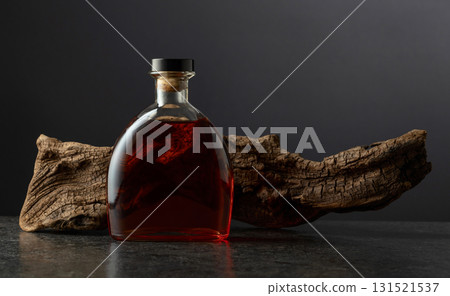 Bottle of brandy and old snag on a black background. Bottle of brandy and old snag on a black background. 131521537