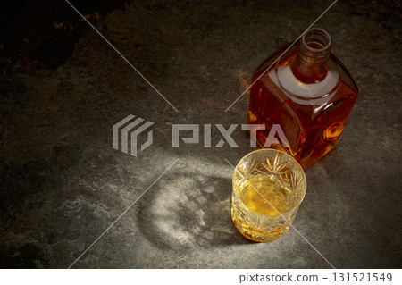 Bottle and crystal glass of whiskey on a stone table. 131521549