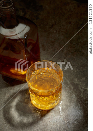 Bottle and crystal glass of whiskey on a old stone table. Bottle and crystal glass of whiskey on a old stone table. 131521550