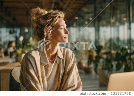 Young woman contemplating, looking away in sunny office 131521798