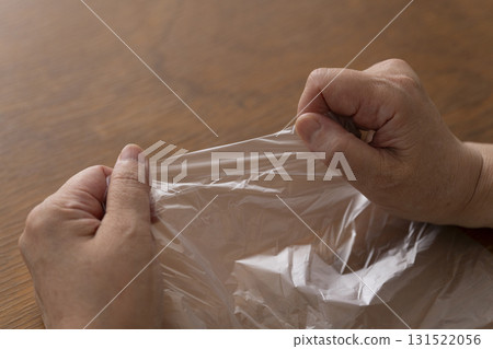 Senior woman's hands are so dry she can't open a plastic bag 131522056