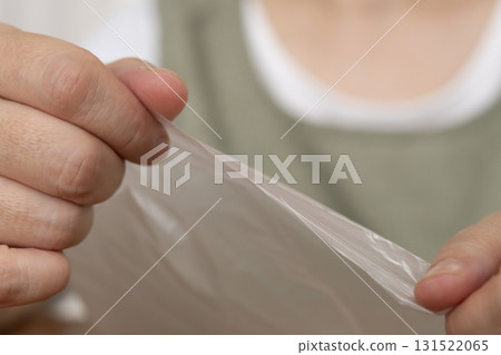 Senior woman's hands are so dry she can't open a plastic bag Senior woman's hands are so dry she can't open a plastic bag 131522065