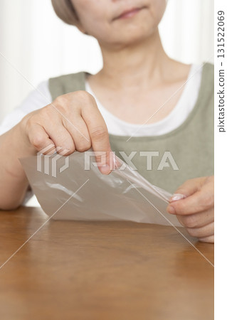 Senior woman's hands are so dry she can't open a plastic bag 131522069