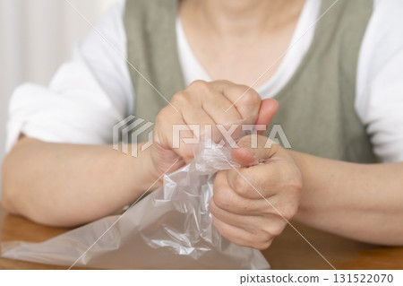 Senior woman's hands are so dry she can't open a plastic bag Senior woman's hands are so dry she can't open a plastic bag 131522070