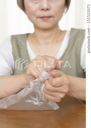 Senior woman's hands are so dry she can't open a plastic bag 131522071