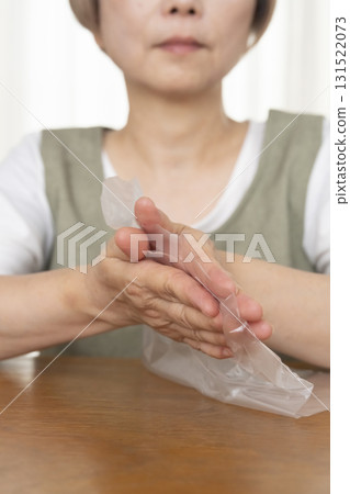Senior woman's hands are so dry she can't open a plastic bag Senior woman's hands are so dry she can't open a plastic bag 131522073