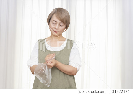 Senior woman whose hands are so dry she can't open a plastic bag Senior woman whose hands are so dry she can't open a plastic bag 131522125
