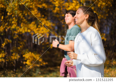 Young beautiful couple jogging in city beautiful autumn park and forest, enjoying outdoor sports 131522205