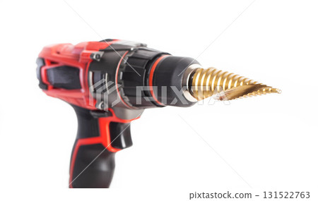 Modern red drill screwdriver with step drill bit in keyless chuck on white background, close-up Modern red drill screwdriver with step drill bit in keyless chuck on white background, close-up 131522763