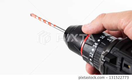 Hand holding a black and red power drill with a drill bit ready for use at a home improvement project, isolate 131522773