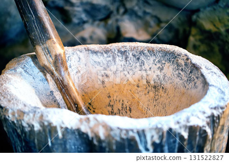 An old mortar with a wooden handle for grinding flour, close-up 131522827