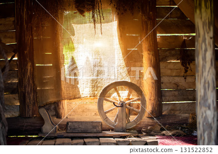 The interior of an old village hut, with a spinning wheel and bunches of dried medicinal herbs in the background of the window, background 131522852