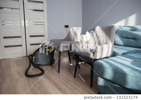 Cleaning equipment ready near grey chairs in a modern living room with sunlight streaming through the window Cleaning equipment ready near grey chairs in a modern living room with sunlight streaming through the window 131523174