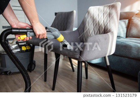 Cleaning a modern upholstered chair with a steam cleaner in a stylish living room Cleaning a modern upholstered chair with a steam cleaner in a stylish living room 131523179