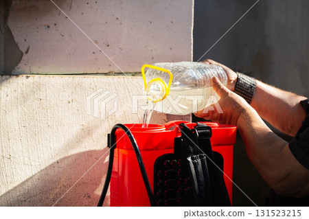 Men's hands pour chemicals into a sprayer to kill parasites on plants. Treatment of plants from diseases and pests. Copy space for text, industry Men's hands pour chemicals into a sprayer to kill parasites on plants. Treatment of plants from diseases and pests. Copy space for text, industry 131523215